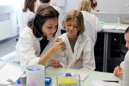 Junge Mädchen im Labor bei der Blutgruppenbestimmung mit Pipette in der Hand