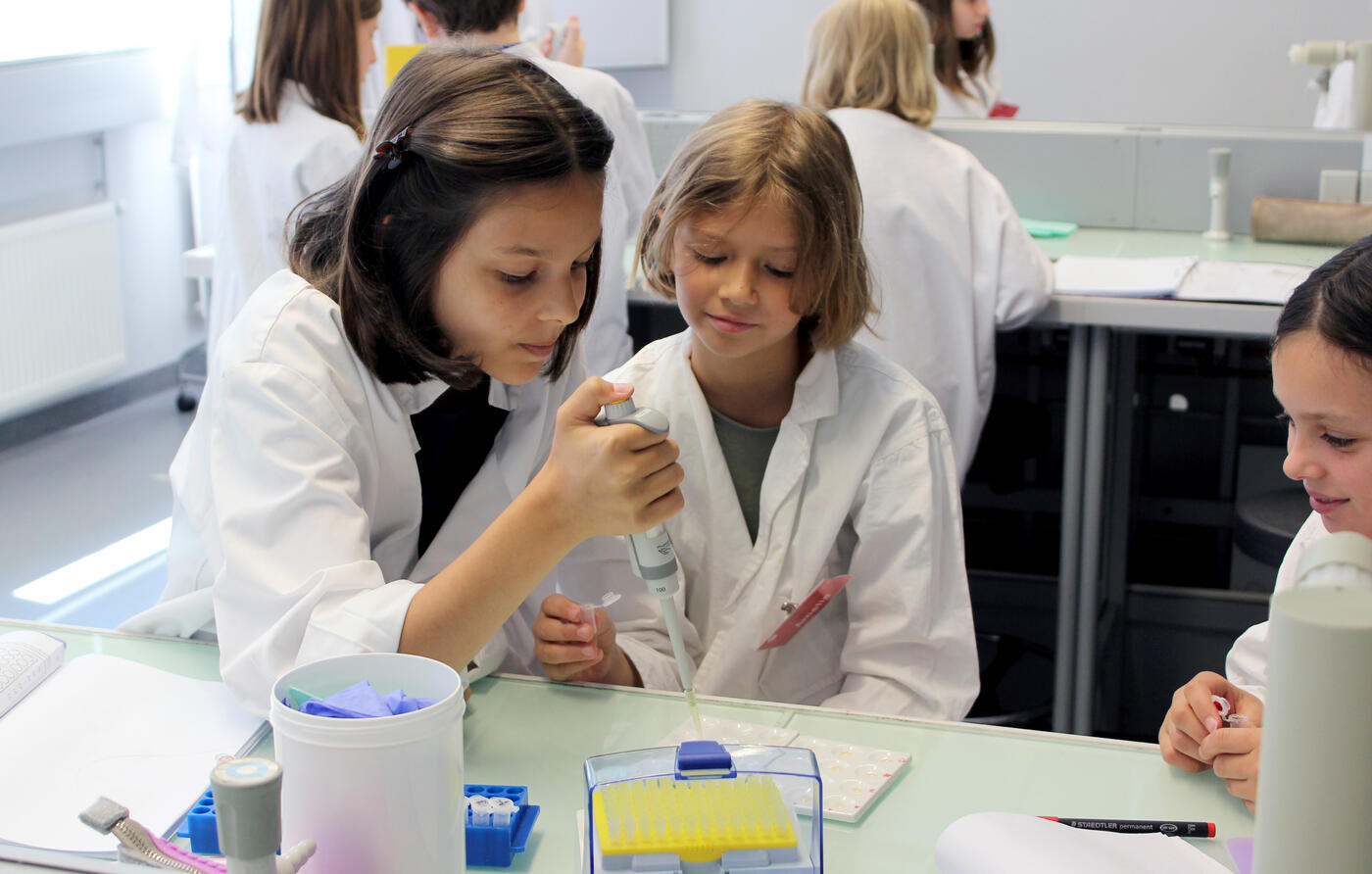 Junge Mädchen im Labor bei der Blutgruppenbestimmung mit Pipette in der Hand