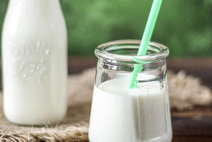 Milch in einer Glasflasche und Milch in einem Glas mit Trinkhalm