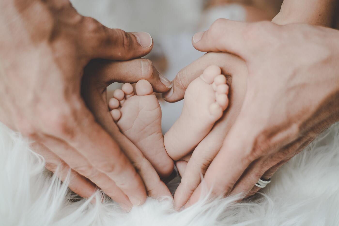 Füße eines Neugeborenen und Hände von Erwachsenen