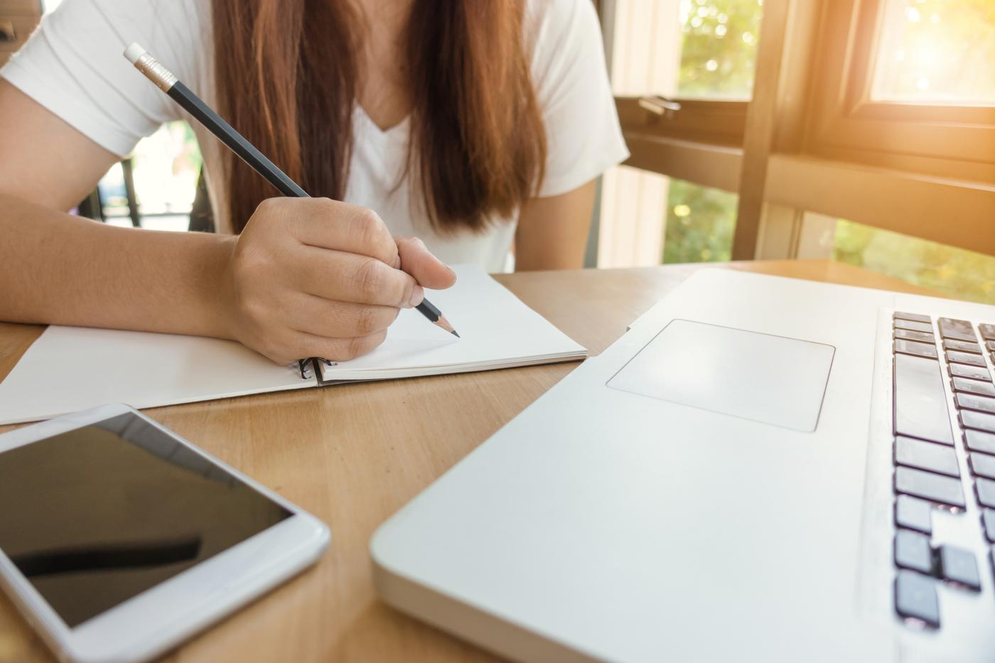 Mädchen das zu Hause vor einem Laptop sitzt und schreibt